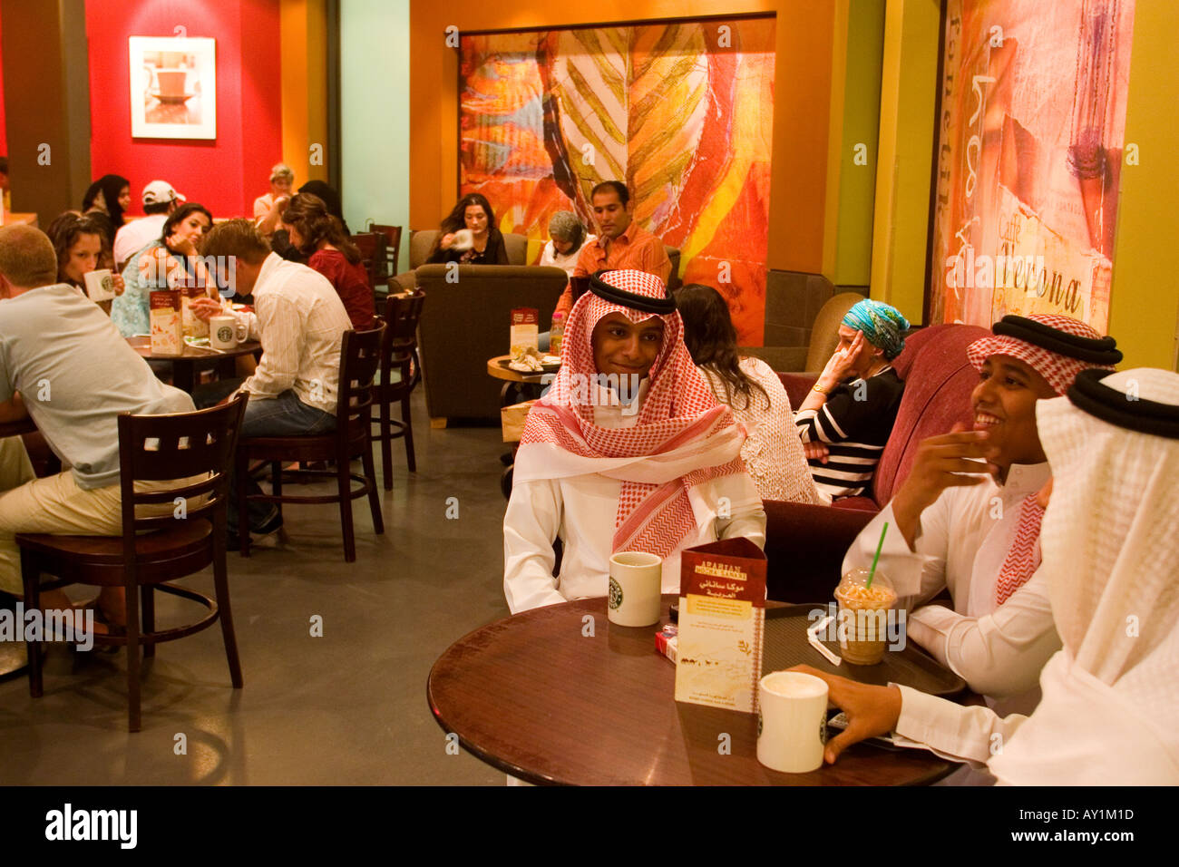 Junge arabische Männer mit traditioneller Kleidung sitzen im Starbucks Café in Deira City Center Einkaufszentrum Dubai Vereinigte Arabische Emirate Stockfoto