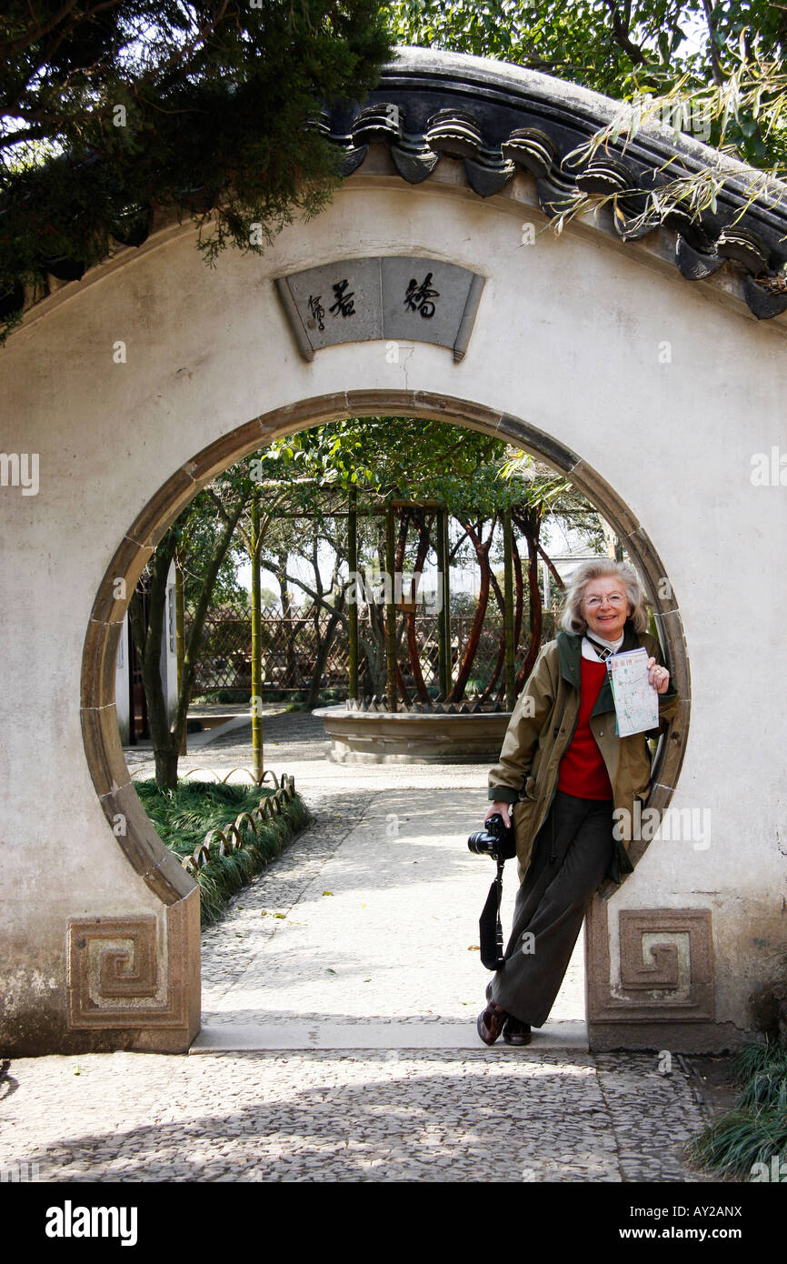 Mond-Tor mit einem Touristen lehnte sich gegen die Wand im Humble Administratoren Garten in Suzhou, China Stockfoto