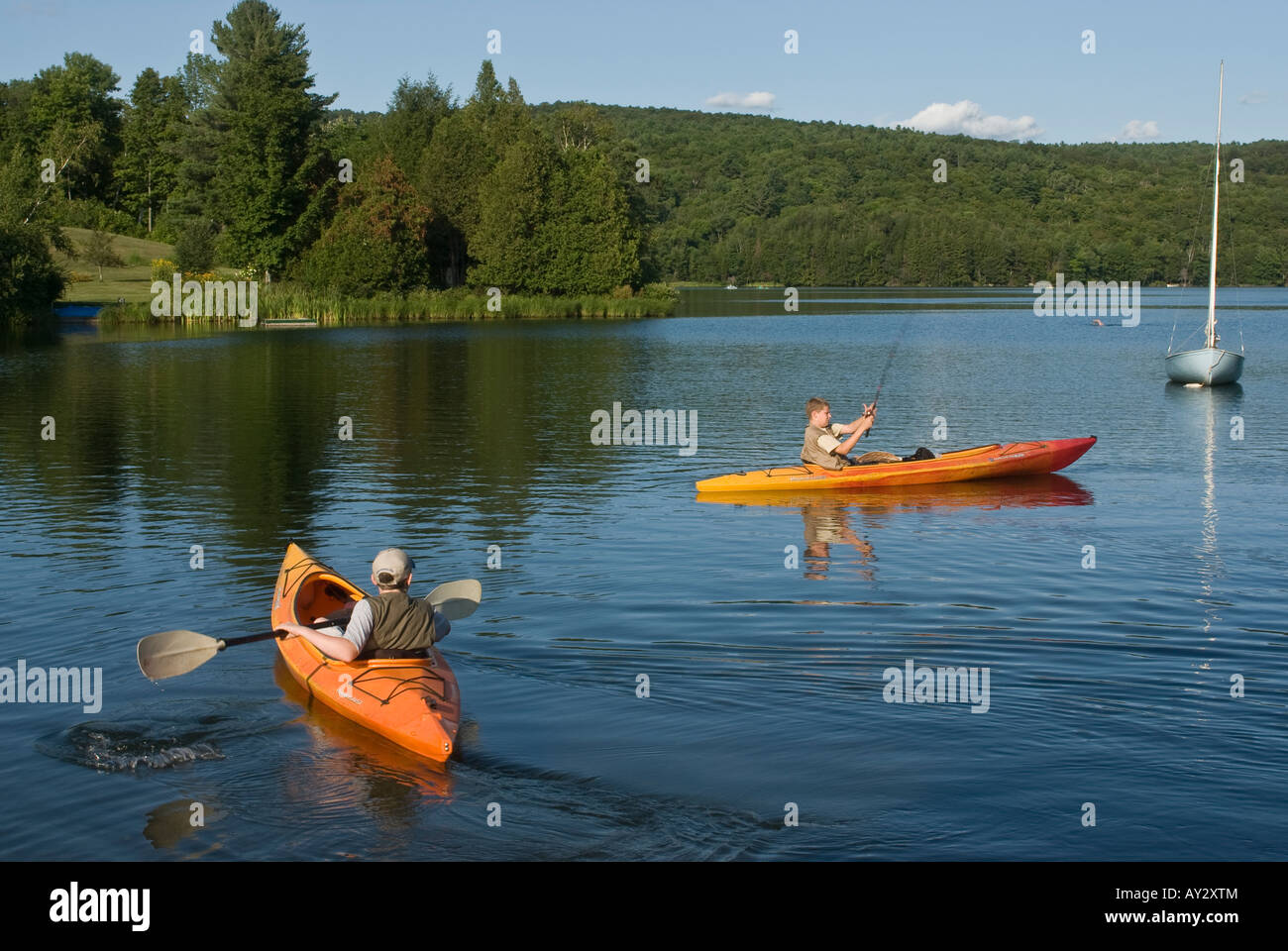 Zwei Teenager, die Angelwesten tragen, angeln aus orangefarbenen Kajaks auf dem Silver Lake Barnard Vermont Stockfoto