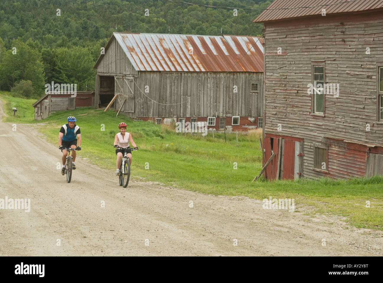 Paar Mountainbikes auf einem ländlichen Feldweg vorbei Reiten verwitterte Scheunen in Warren Vermont an einem bewölkten Sommertag Stockfoto