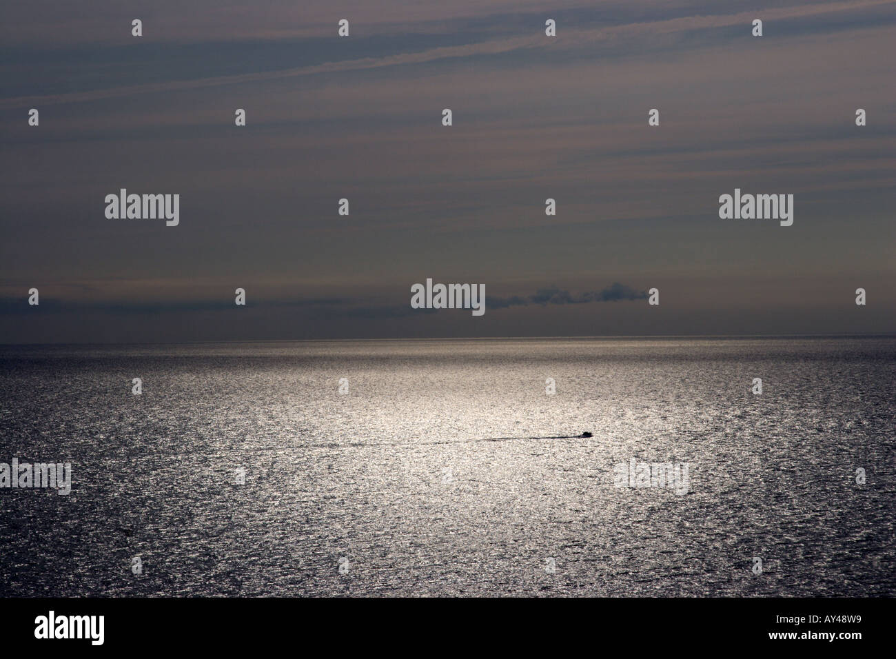Ein kleines Boot schneidet über den Ozean in der Abenddämmerung Stockfoto
