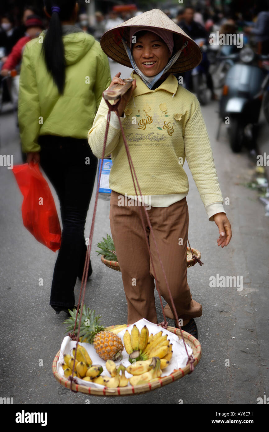 Frau, die eine traditionelle vietnamesische "Don Ganh" Joch, Altstadt, Hanoi, Vietnam Stockfoto