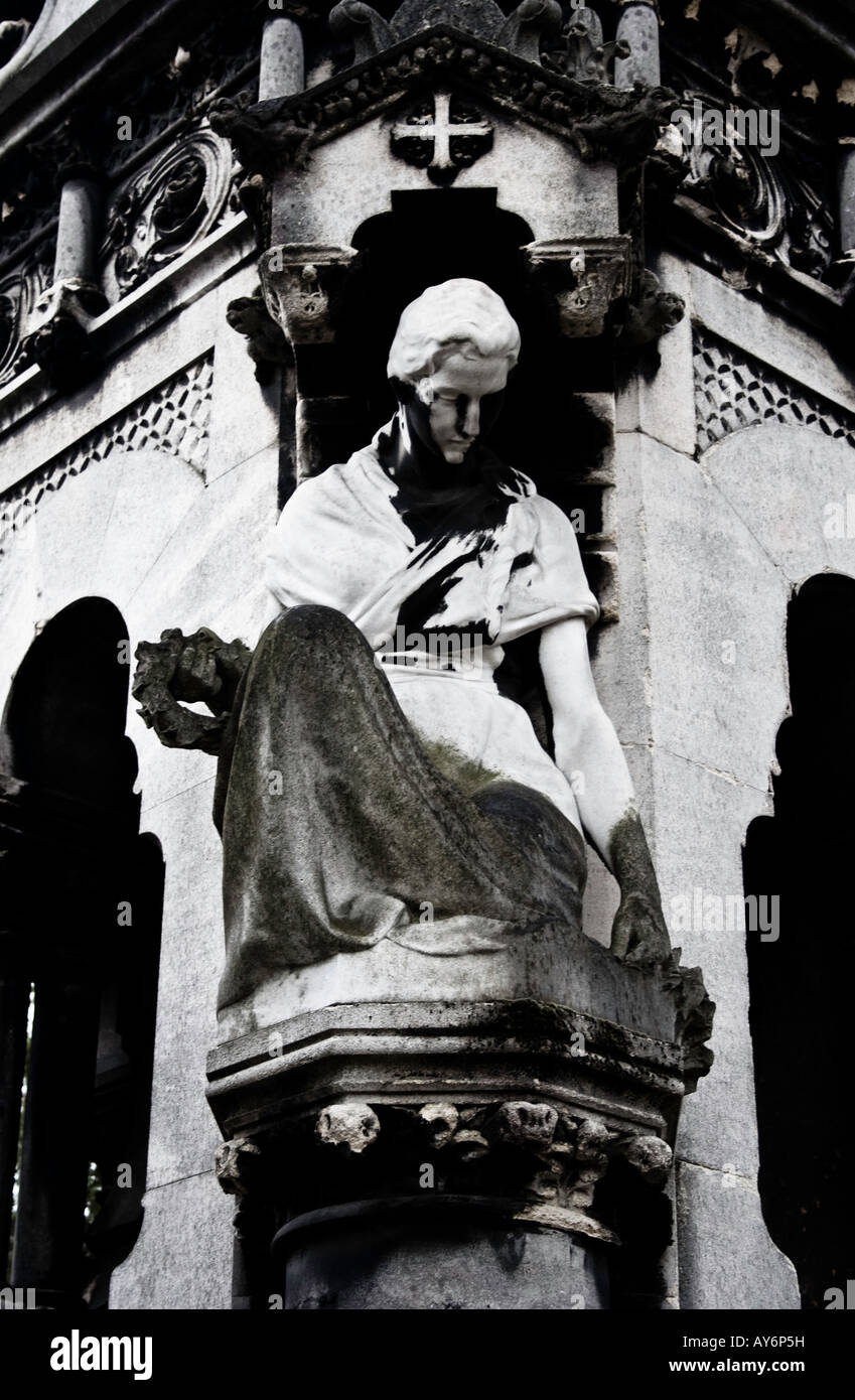 Eine Frau, die Dekoration ein Grab am Pere Lachaise fällt in zwei Arten von Flechten einer schwarz die andere grün. Stockfoto