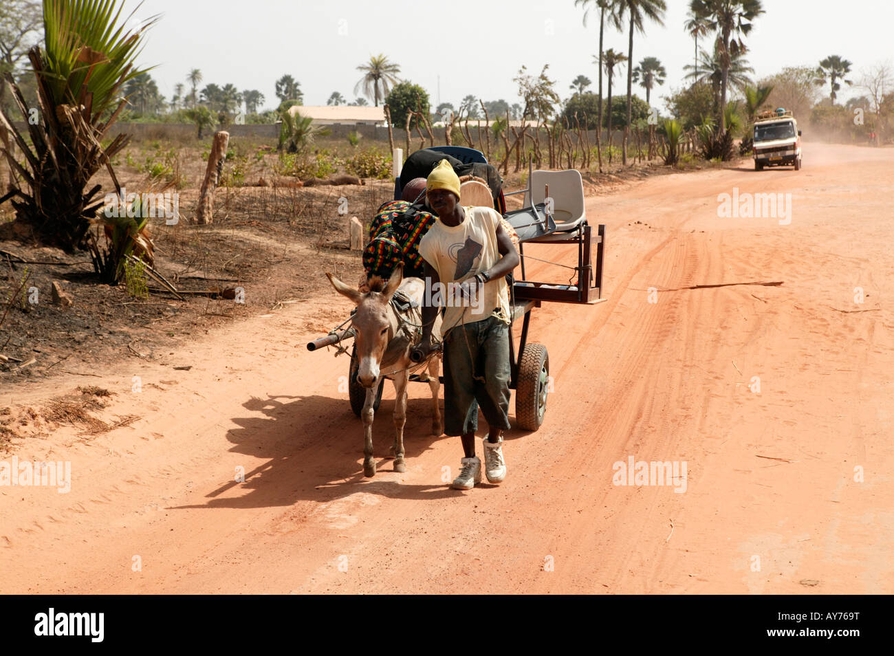 Mann mit Esel und Wagen mit Buschtaxi im Hintergrund The Gambia Westafrika Stockfoto