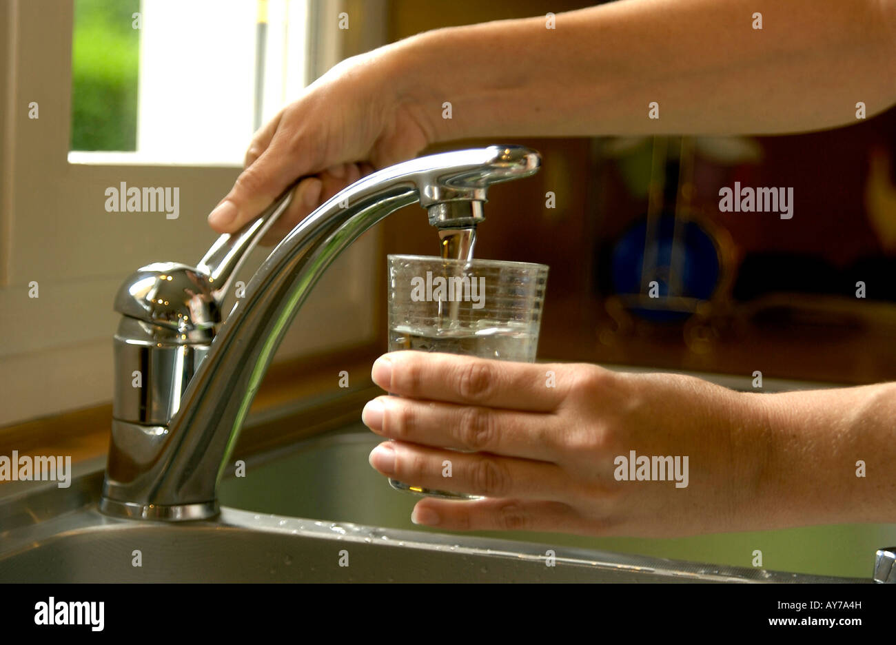 Frau füllt ein Glas Wasser aus der Küchenarmatur Spüle Stockfoto