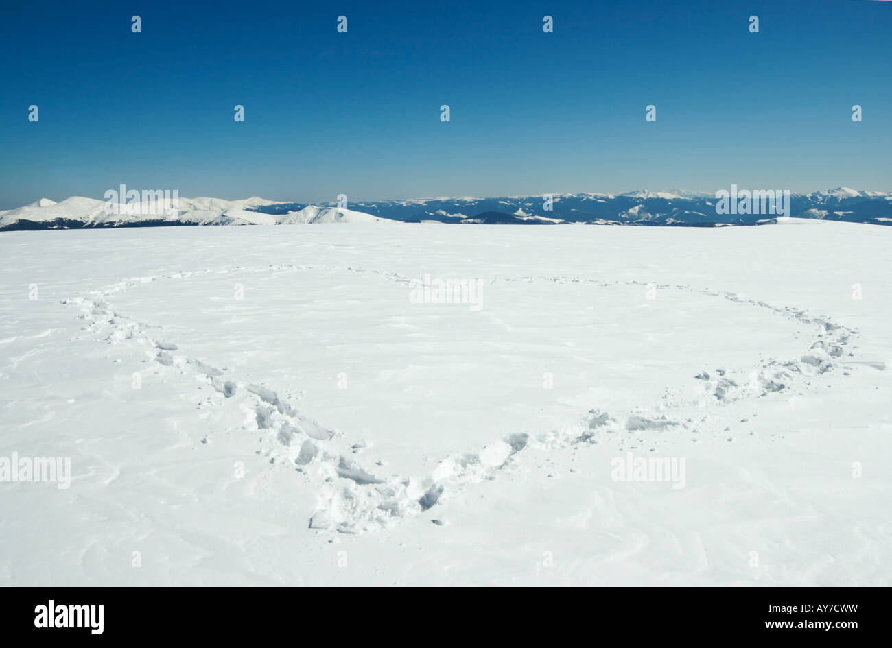 Menschlichen Fußabdruck bilden die Herzform auf Schnee bedeckten Berg-Plateau und Bergketten hinter Stockfoto