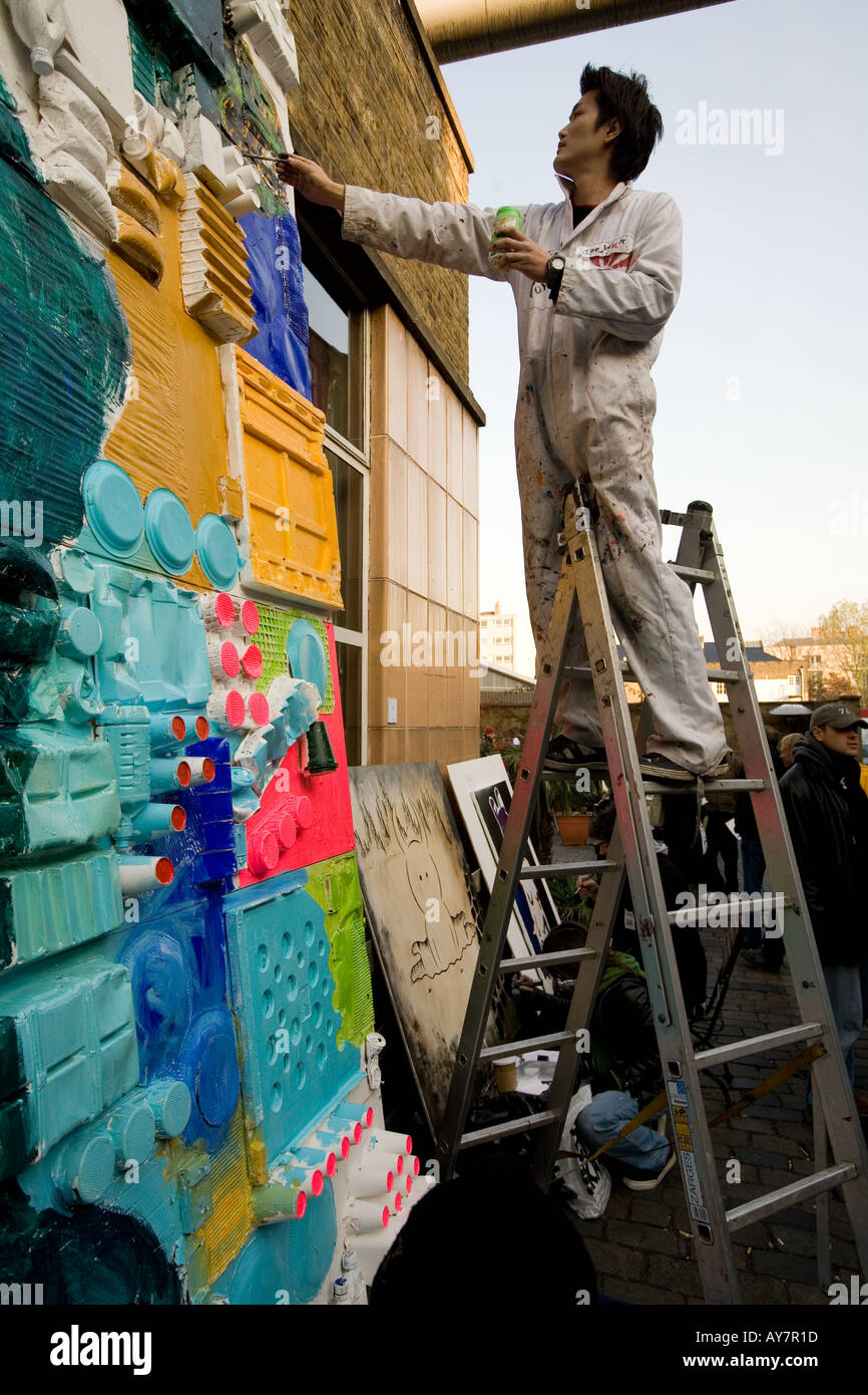 Japanischer junge Künstler Malerei an einer freien Kunst zeigen Brick Lane London uk Stockfoto