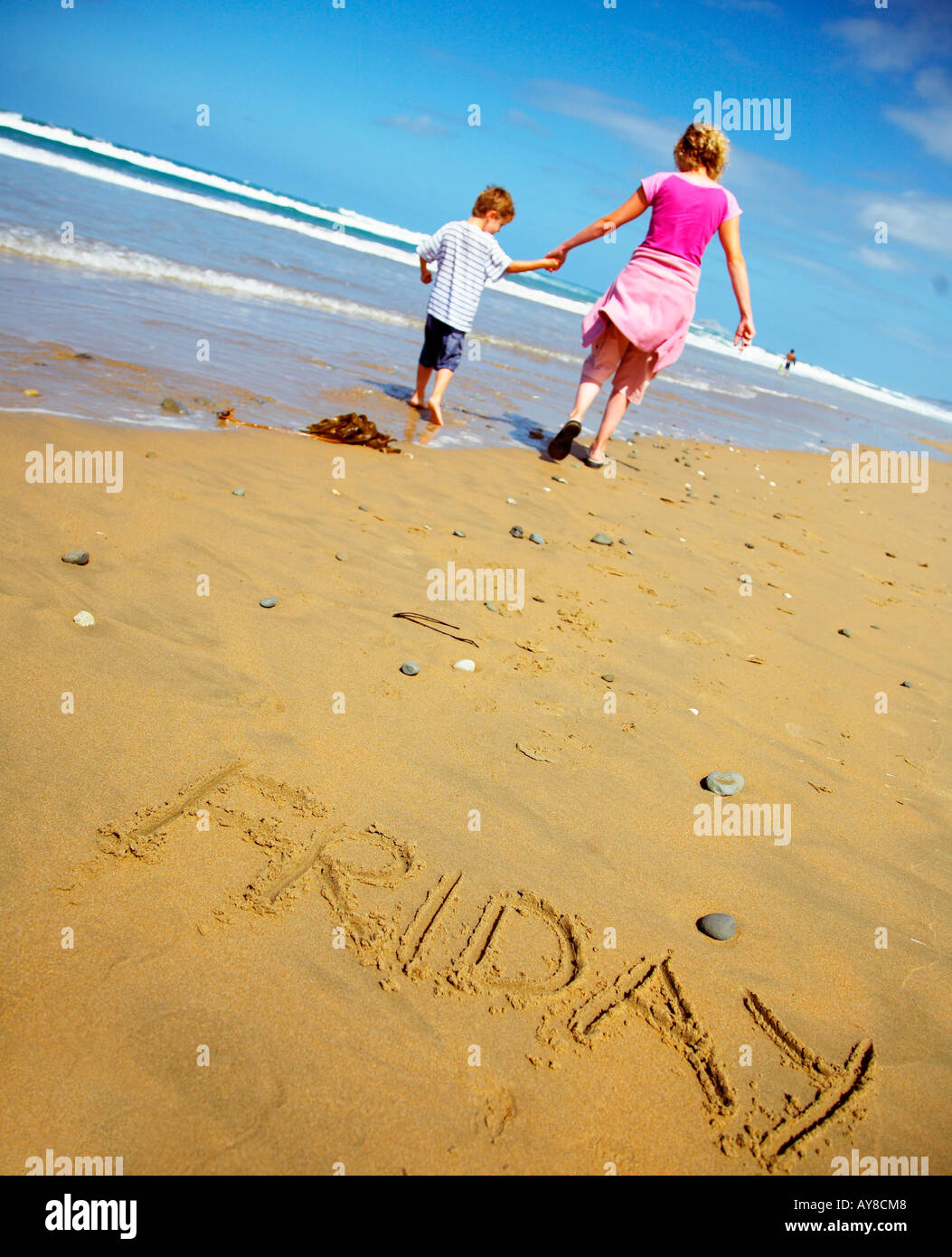 das Wort Freitag gezogen in den Sand mit Menschen am Strand bereit für das Wochenende Stockfoto