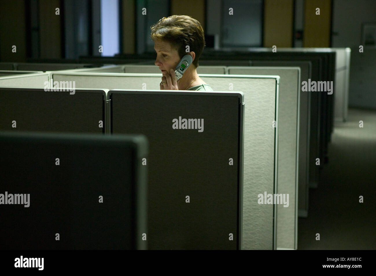 Arbeitnehmerin auf Handy während der Arbeit nach Stunden im Schrank-Büro Stockfoto