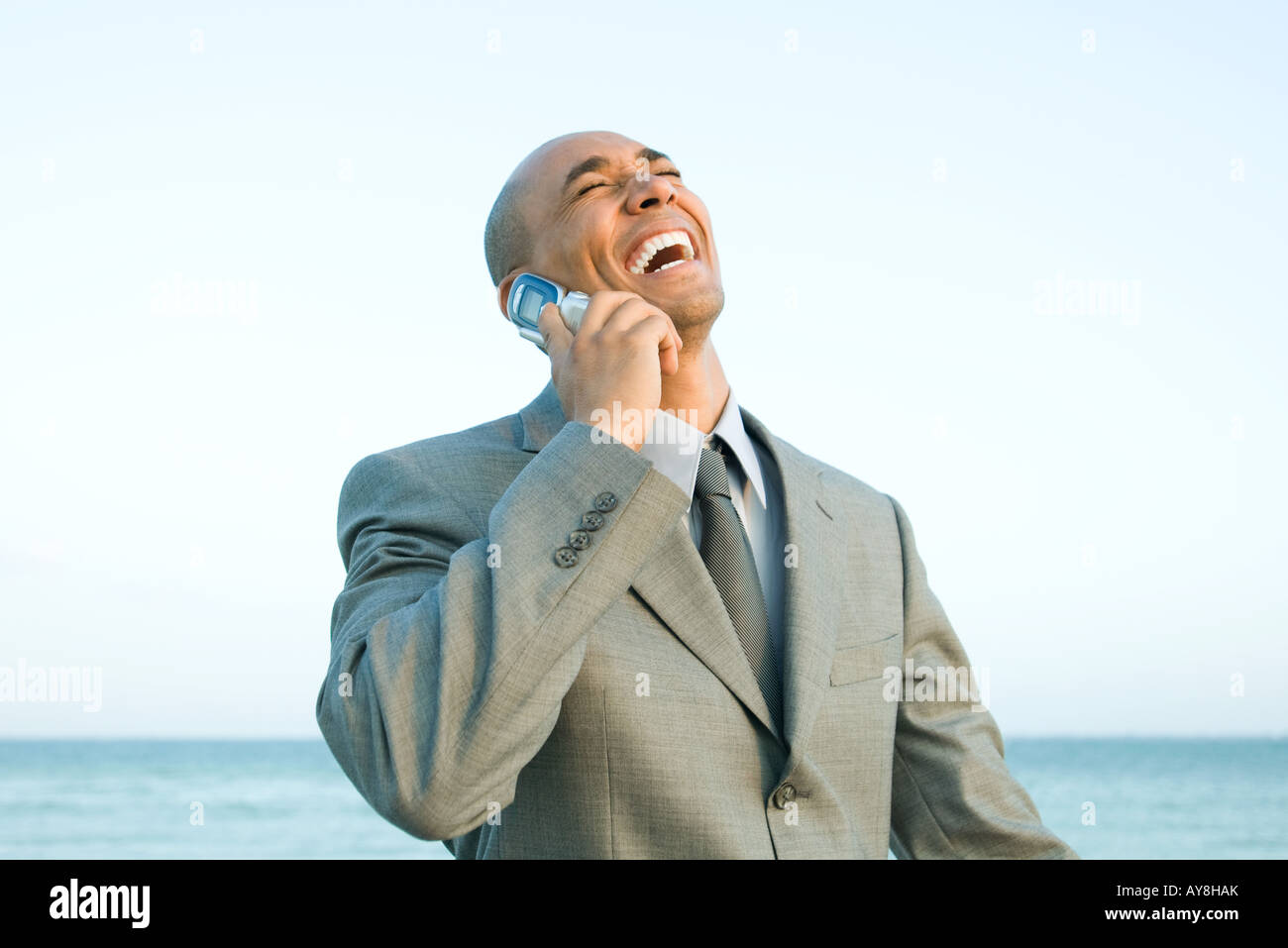 Geschäftsmann am Strand mit Handy, lachen, Augen geschlossen Stockfoto