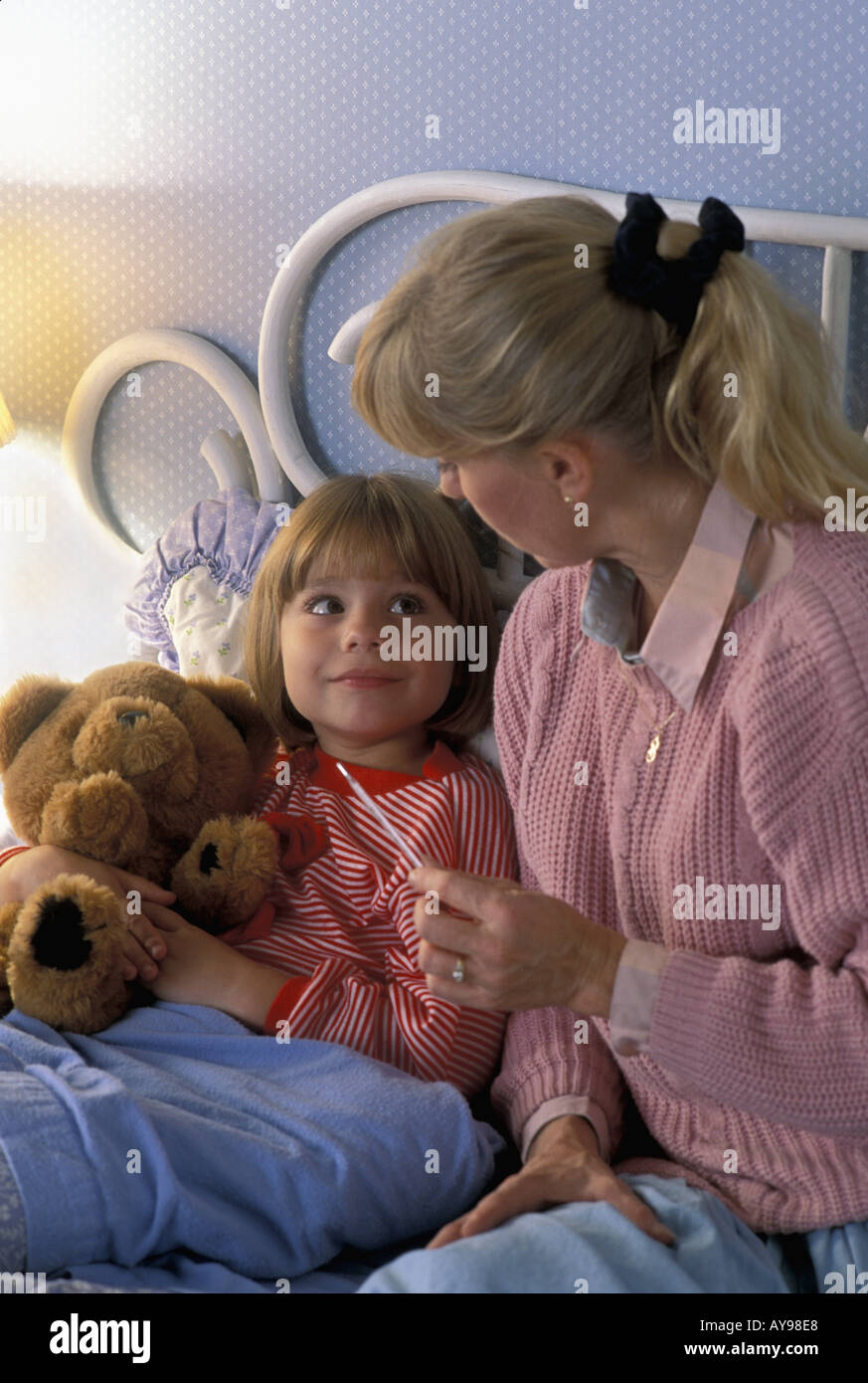 Mutter mit Messung der kranken Tochter mit kaltem Stockfoto