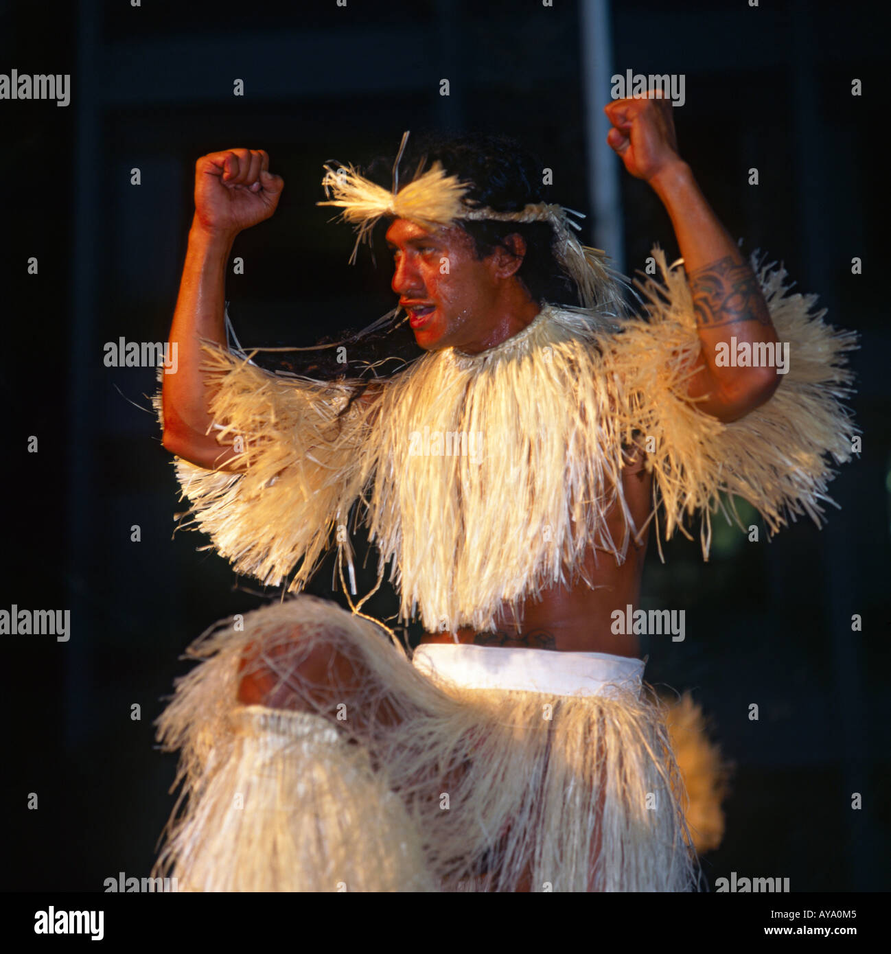 Lächelnd Tahitian Tänzer in Tracht trägt Grass Rock & Top mit Stirnband und erhobenen Armen Stockfoto