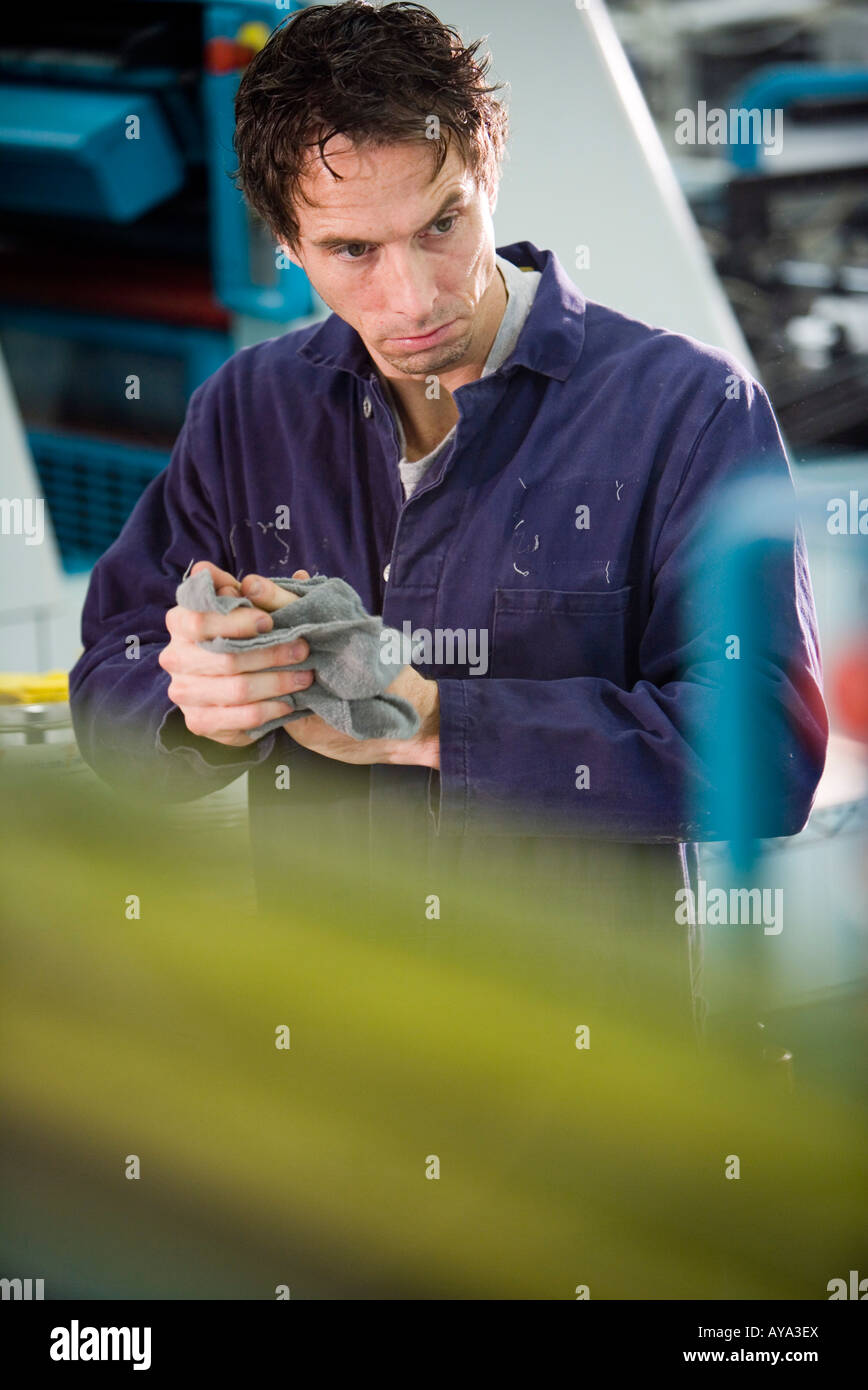 Ansicht eines Mannes in Overalls wischte seine Hände vor einige Maschinen Stockfoto