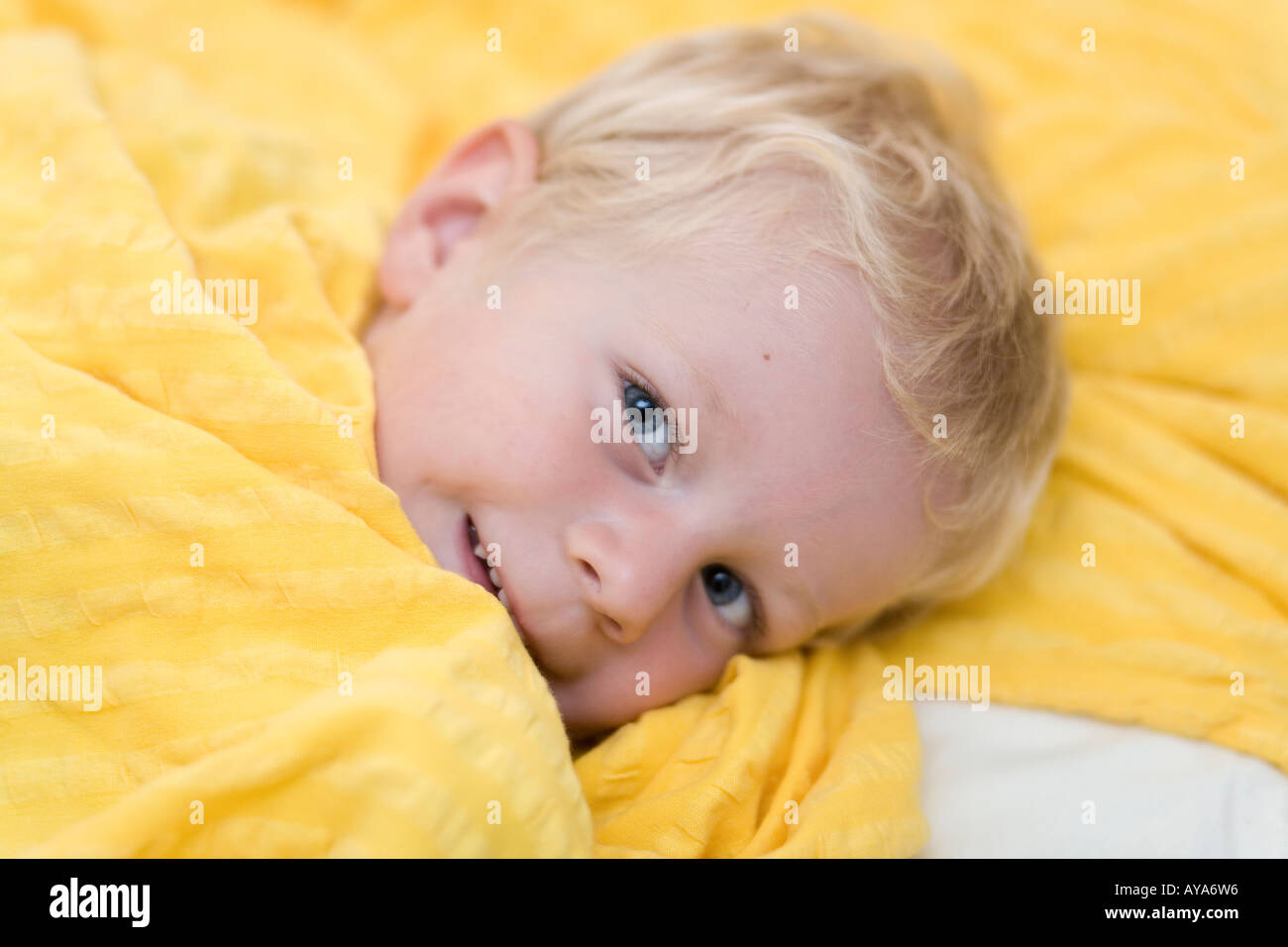Ein drei Jahre alter Junge kuschelt sich in seinem Bett Stockfoto
