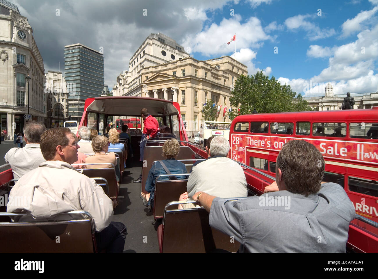 Londoner Trafalgar Square an Bord offen Top Tour sightseeing Bus Fahrgäste mit normalen Bus vorbei Werbung Harrods Verkauf Stockfoto