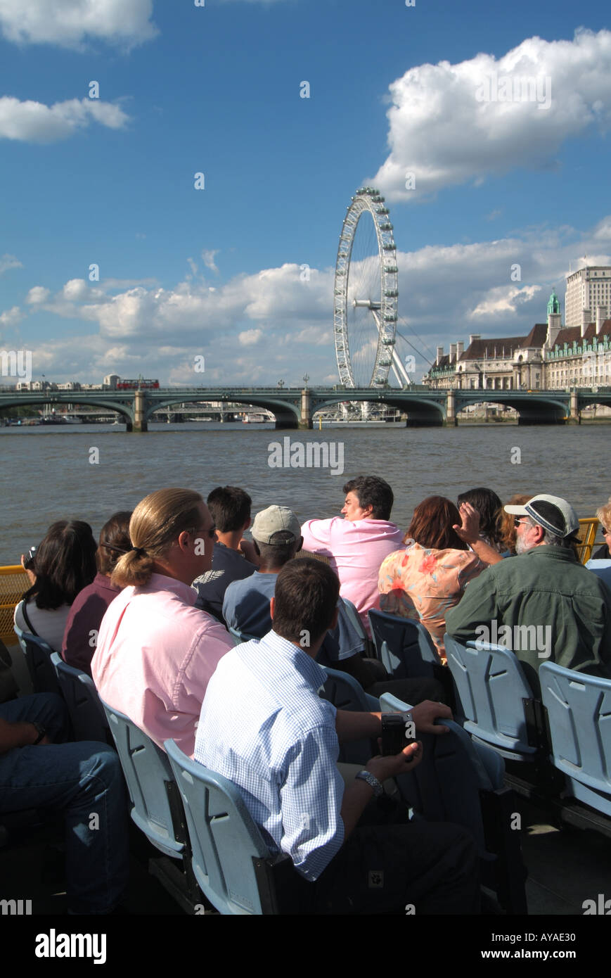 Themse tour Boot Passagiere in ihre Sitze für Tourismus Sehenswürdigkeiten in der Nähe von Westminster Bridge mit London Eye Riesenrad über England Großbritannien Stockfoto