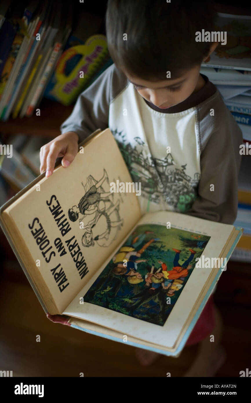 Jungen im Alter von sechs Jahren liest Buch der Märchen und Kinderreime Stockfoto