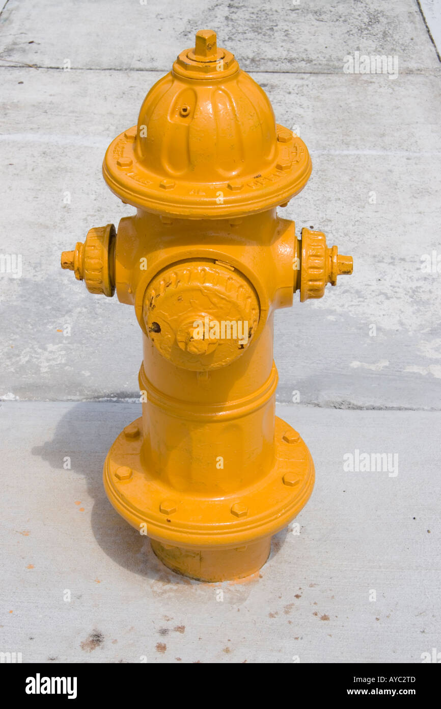 ein helle gelbe Hydranten ragt aus dem Bürgersteig Stockfoto