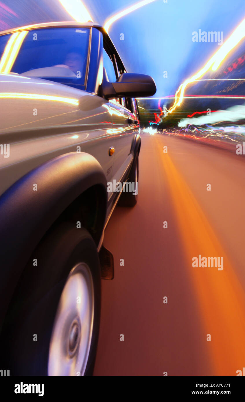 Seitenansicht des Suv fahren bei Nacht mit Straße und Lichter, die Unschärfe im Hintergrund Stockfoto