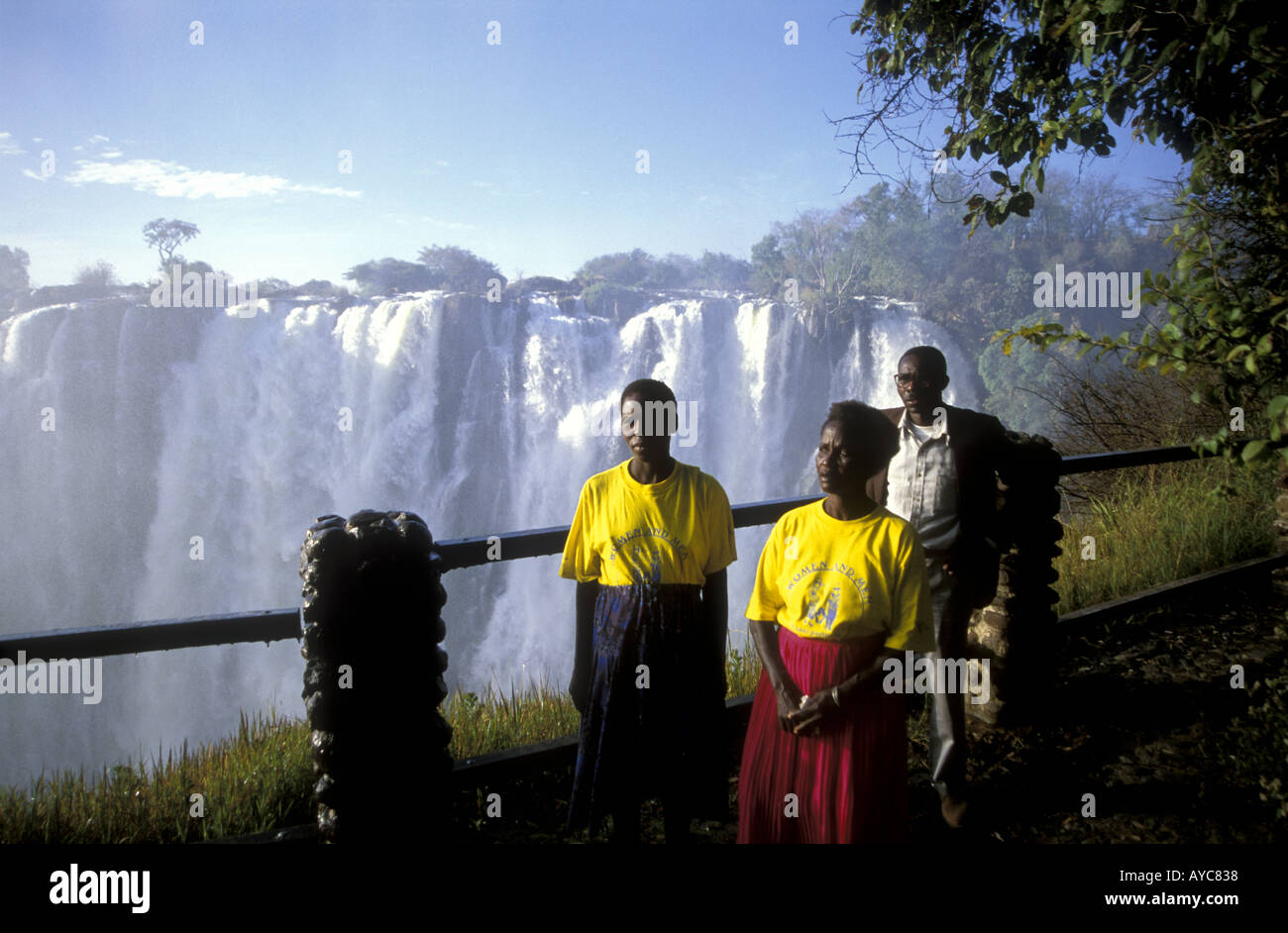 Zwei afrikanische Frauen und ein Mann darstellen an der Sambia-Seite der Viktoriafälle Afrika Stockfoto