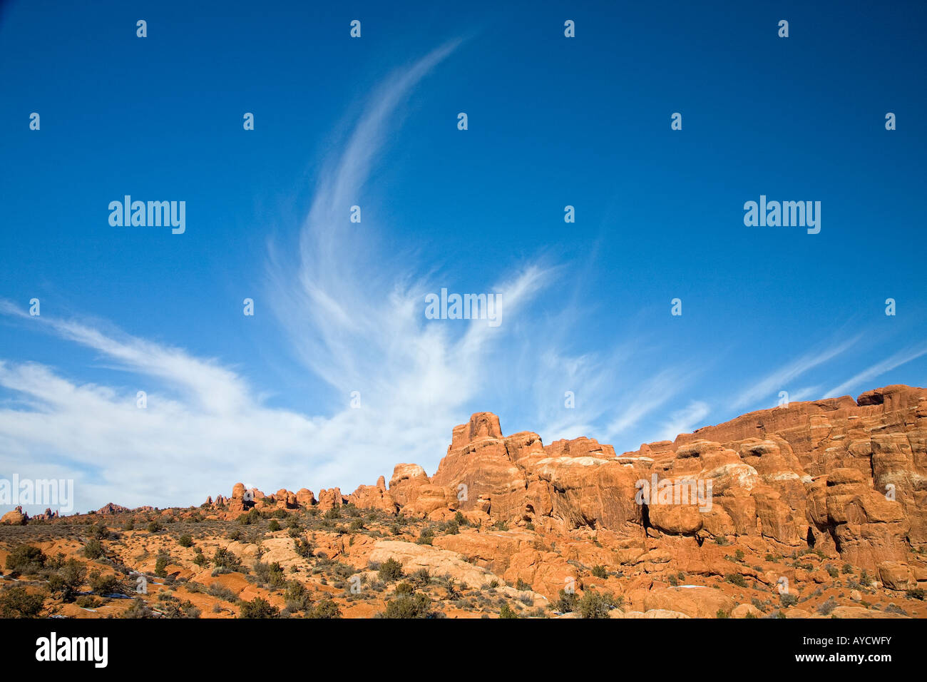 Whispy Wolkenformationen über Felsformationen mit Winterschnee im Arches National park Stockfoto