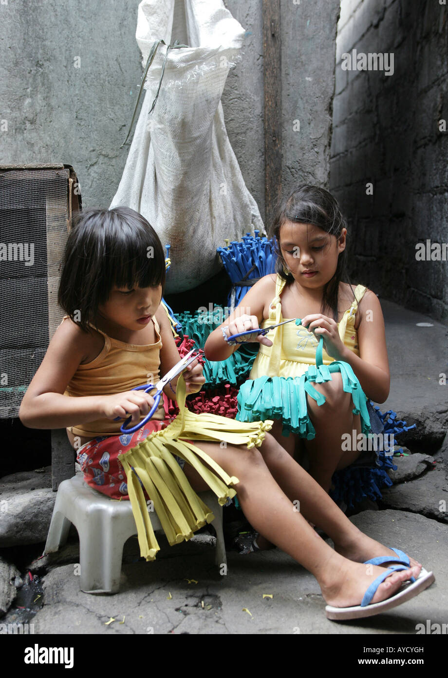 Manila: Mädchen (8 Jahre alt) schneiden Sie die Reste der Schleifen von Kautschuk Hausschuhe in Hausaufgaben Stockfoto