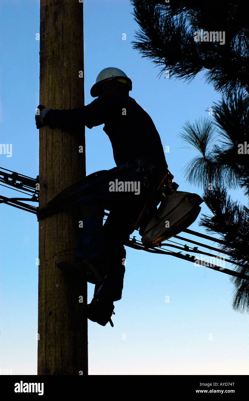 Silhouette eines Elektrikers Klettern eine neu installierte Strommast Stockfoto