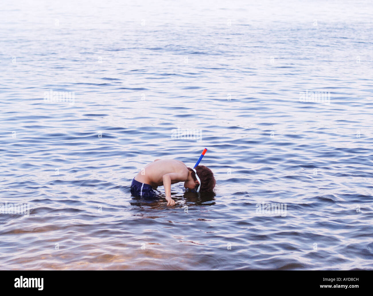 Kleiner Junge spähen unter der Oberfläche des Wassers mit einem Schnorchel und Maske Stockfoto