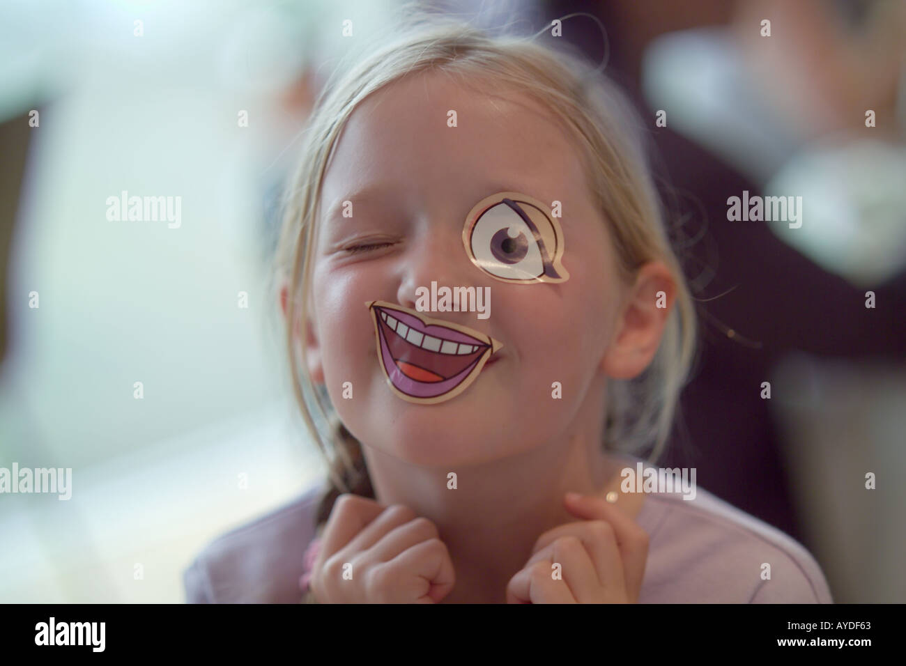 sieben Jahre altes Mädchen mit Stick auf Mund und Augen Stockfoto