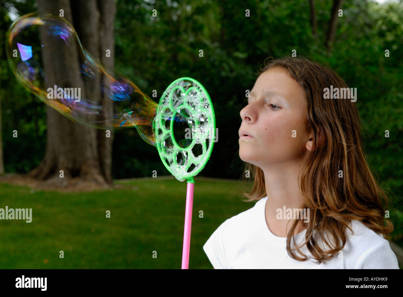 Junges Mädchen bläst Riesen Seifenblase außerhalb auf Rasen Stockfoto