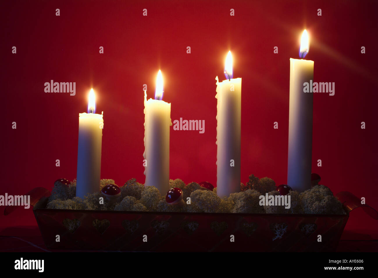 Vier weiße Advent Kerzen vor einem roten Hintergrund Stockfoto
