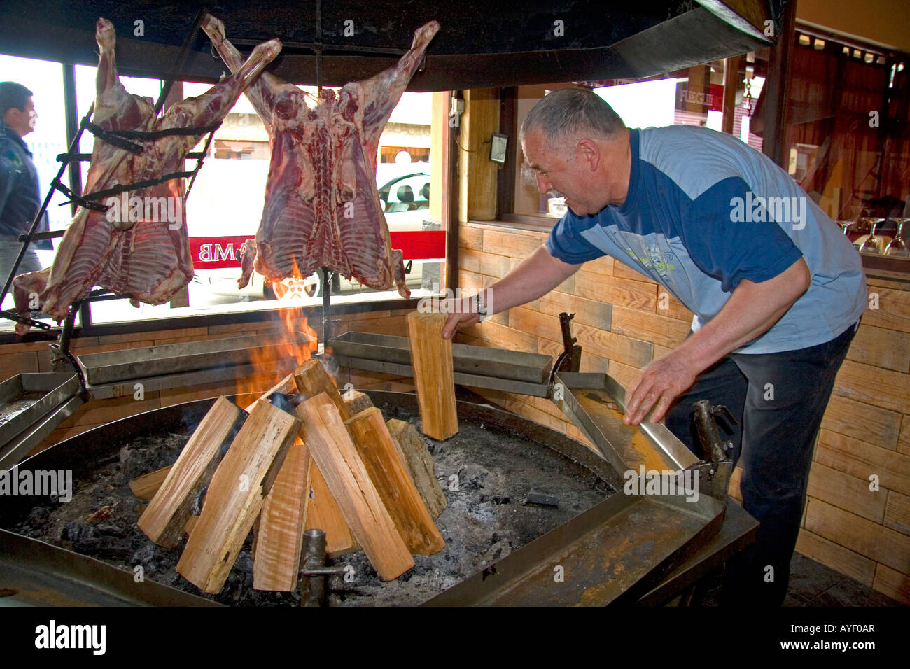 Mann, Kochen von Fleisch über dem offenen Feuer in einem Restaurant in Ushuaia auf der Insel von Tierra Del Fuego Argentinien Stockfoto