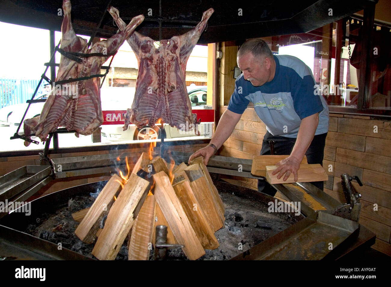 Mann Kochen Lammfleisch über dem offenen Feuer in einem Restaurant in Ushuaia auf der Insel von Tierra Del Fuego Argentinien Stockfoto