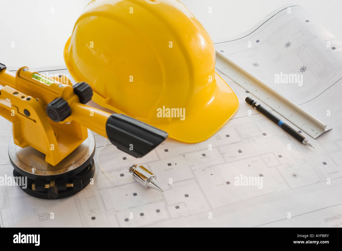 Schutzhelm und Vermessungsgeräte auf Blaupausen Stockfoto