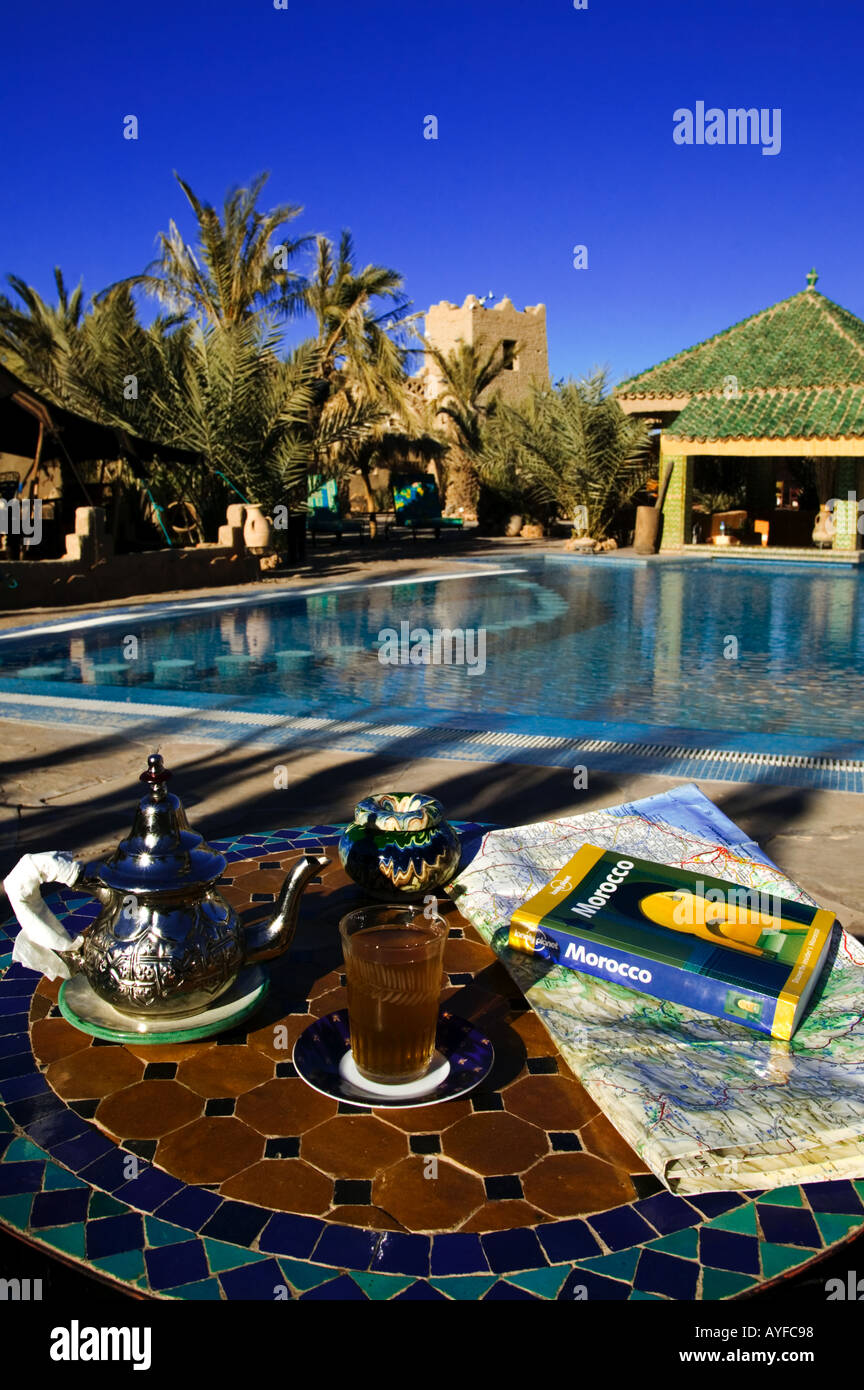Traditioneller Tee und touristische Reiseführer neben Schwimmbad der Kasbah Gesangs-Maadid Hotel Stadt von Erfoud, Marokko Stockfoto