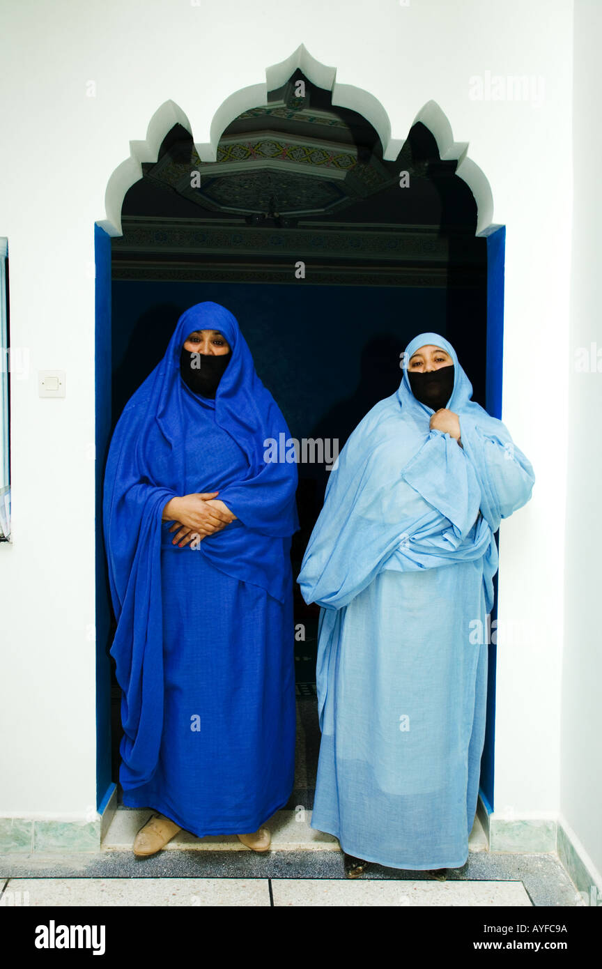 Muslimische Frauen tragen die traditionelle Tschador oder Nikab Stände umrahmt von einem Rundbogen Marokko Stockfoto