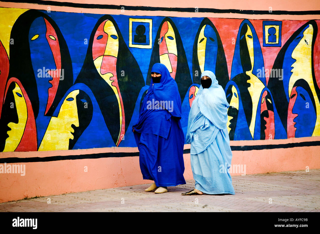 Muslimische Frauen tragen traditionelle Tschador oder Nikab vorbeigehen eine bunte Wandgemälde, die Darstellung der muslimischen Frauen Marokko Stockfoto
