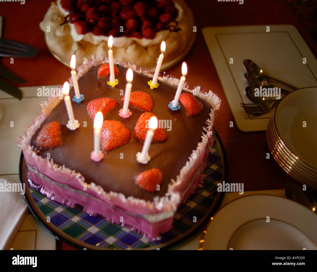Brennende Kerzen auf einem Geburtstagsschokolade Cakewith Erdbeeren obenauf Stockfoto