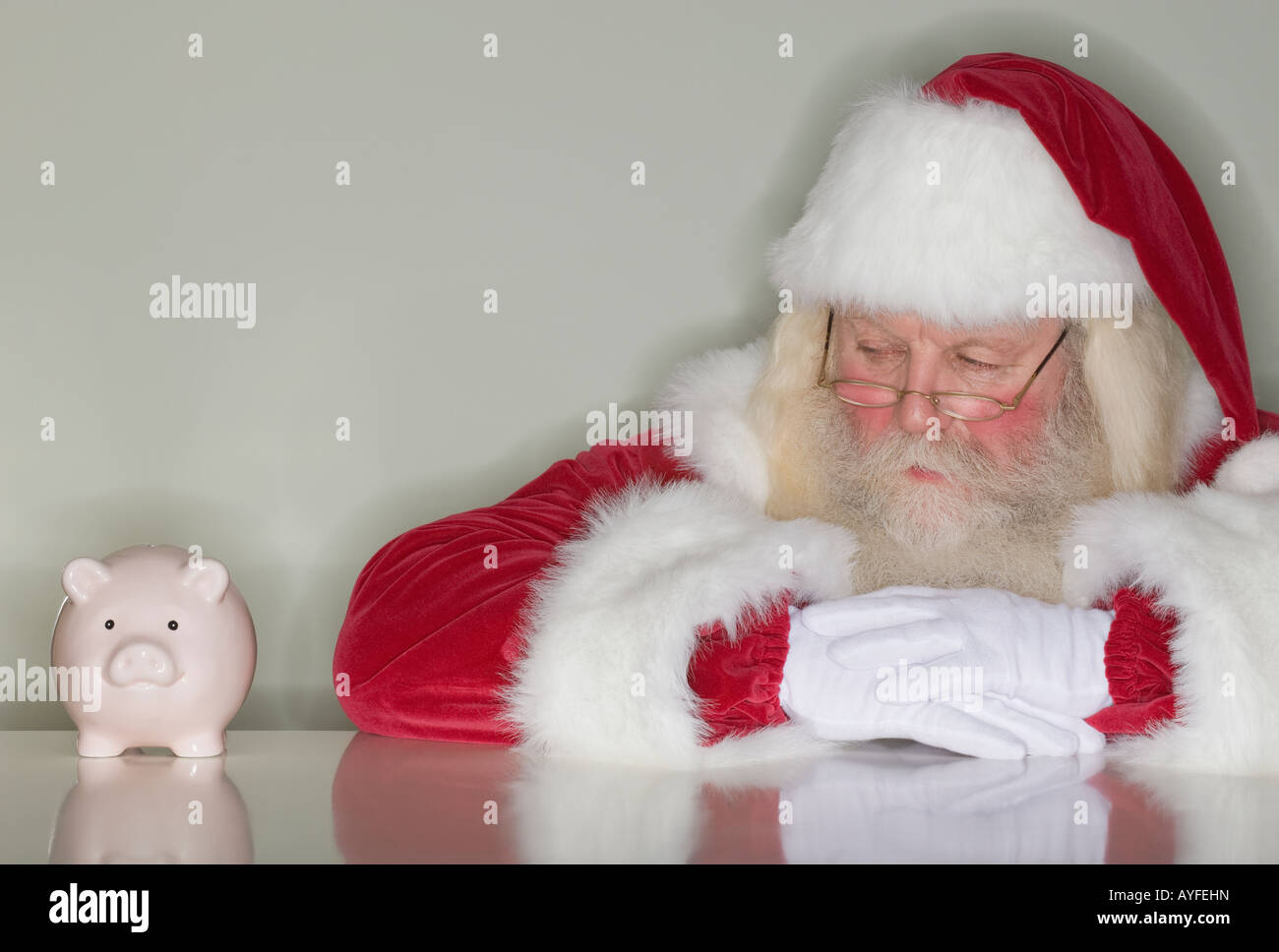 Santa Claus betrachten Sparschwein Stockfoto