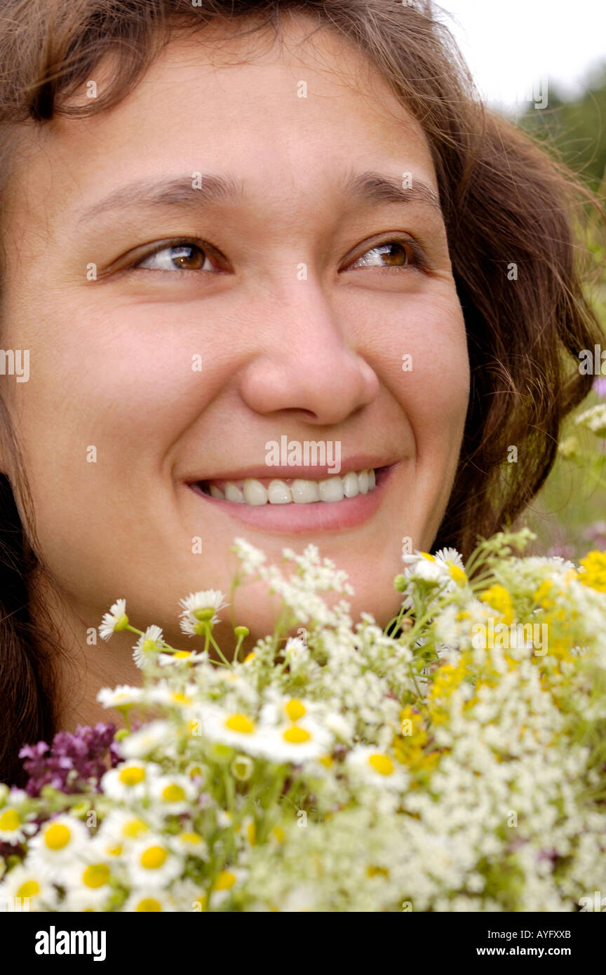 Glückliche Frau mit Haufen von Kamillen in der Natur Stockfoto