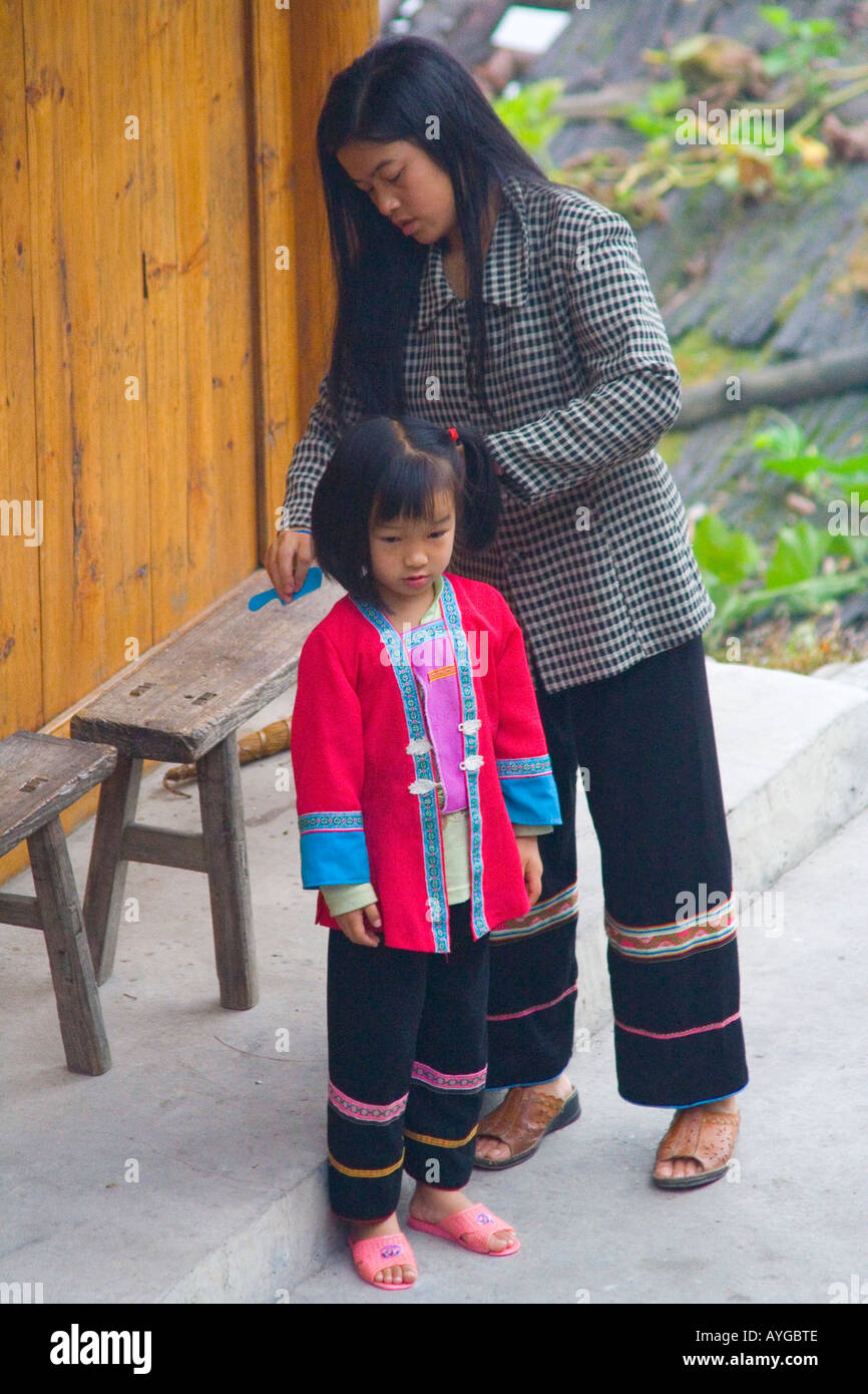 Zhuang Minderheit Mutter Kämmen junge Tochter tragen traditionelle Kleidung Ping An Longsheng China Stockfoto