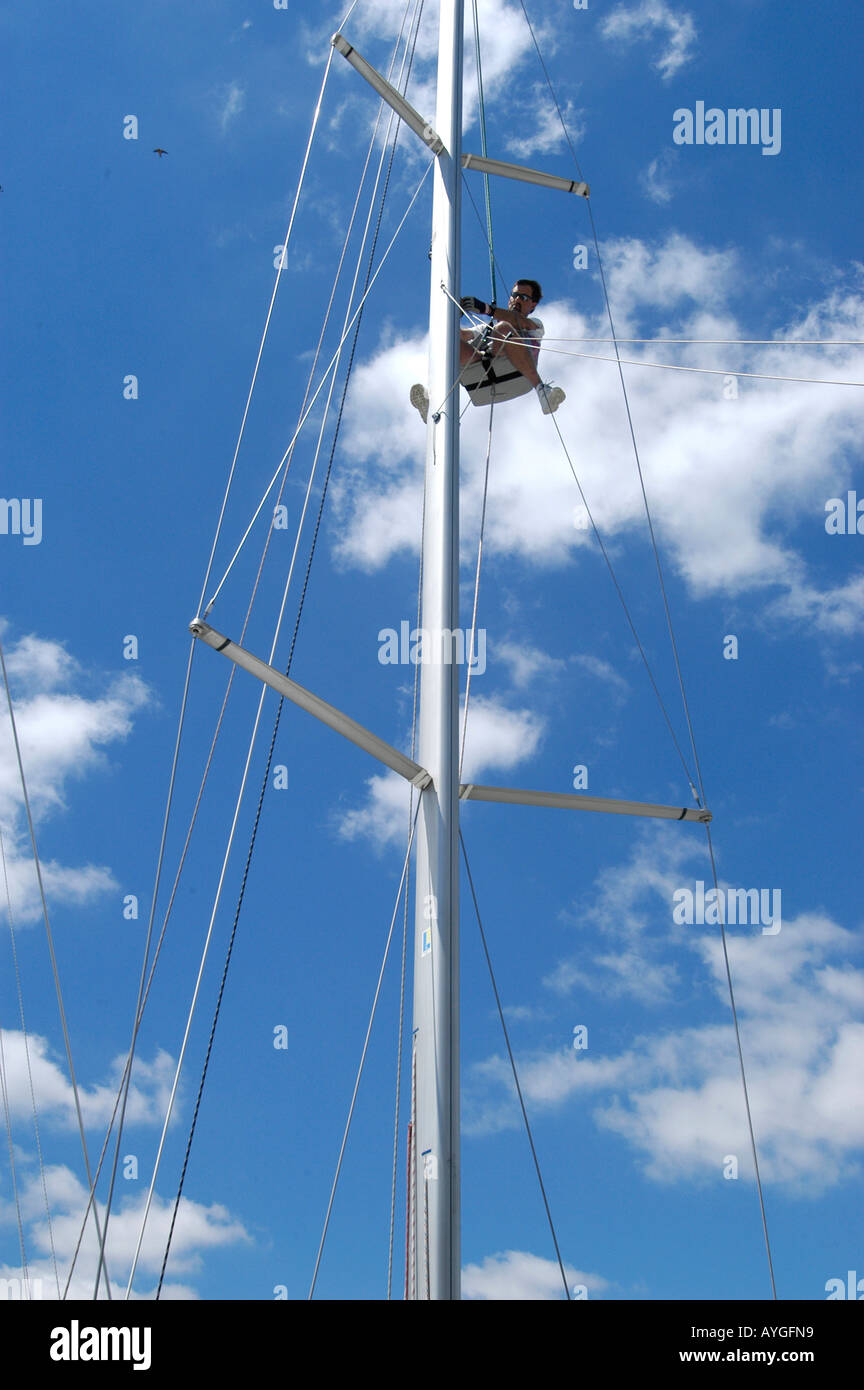 Crew-Mitglied geht auf den Mast eines Segelbootes Reparaturen und Maintence durchführen Stockfoto