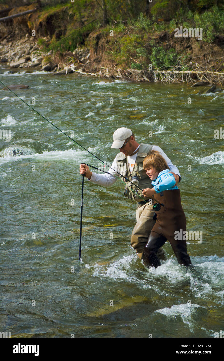 Vater und Sohn einen Berg-Fliegenfischen-Fluss überquert Stockfoto