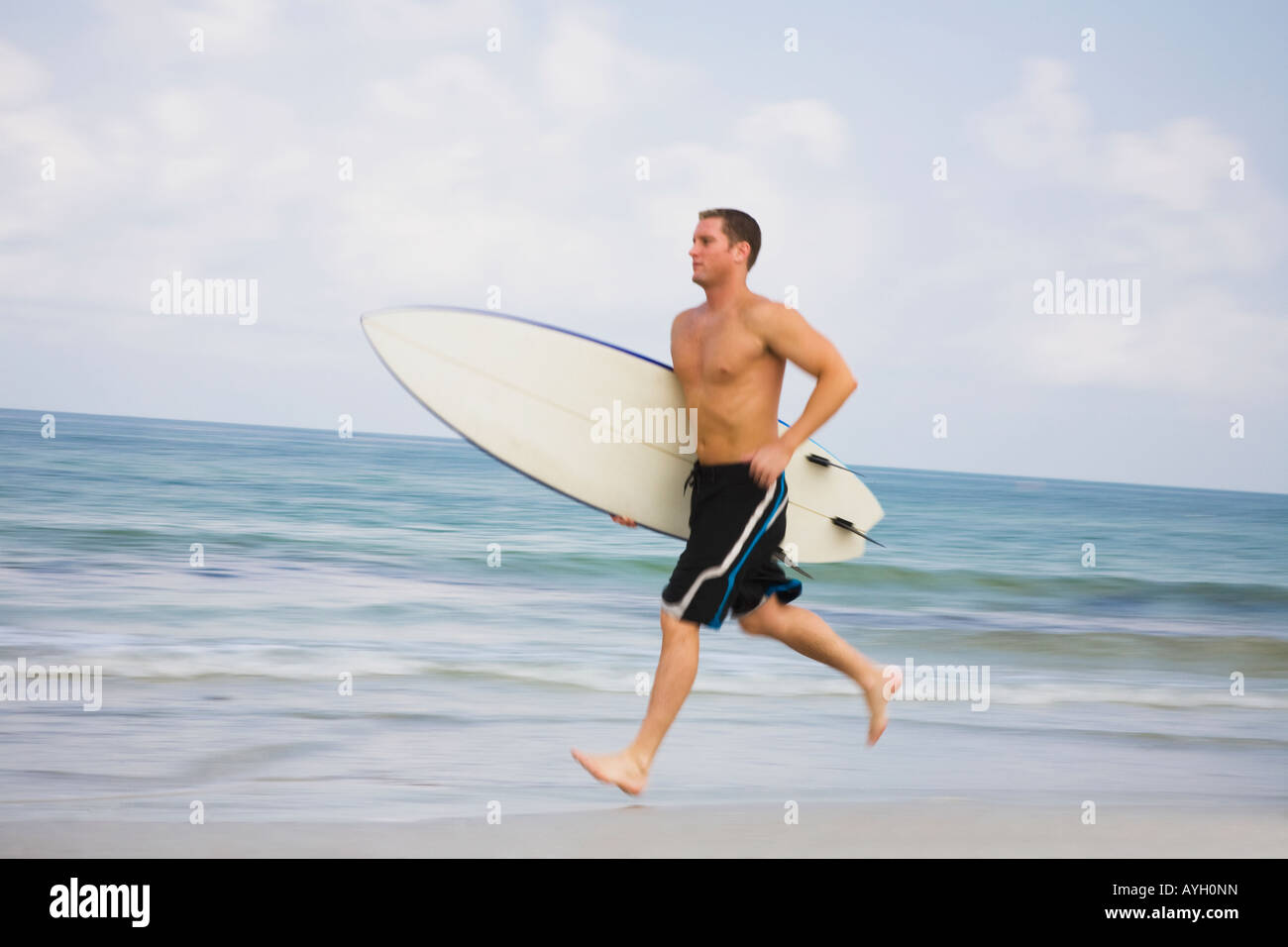 Nacktem Mann läuft mit Surfbrett Stockfoto