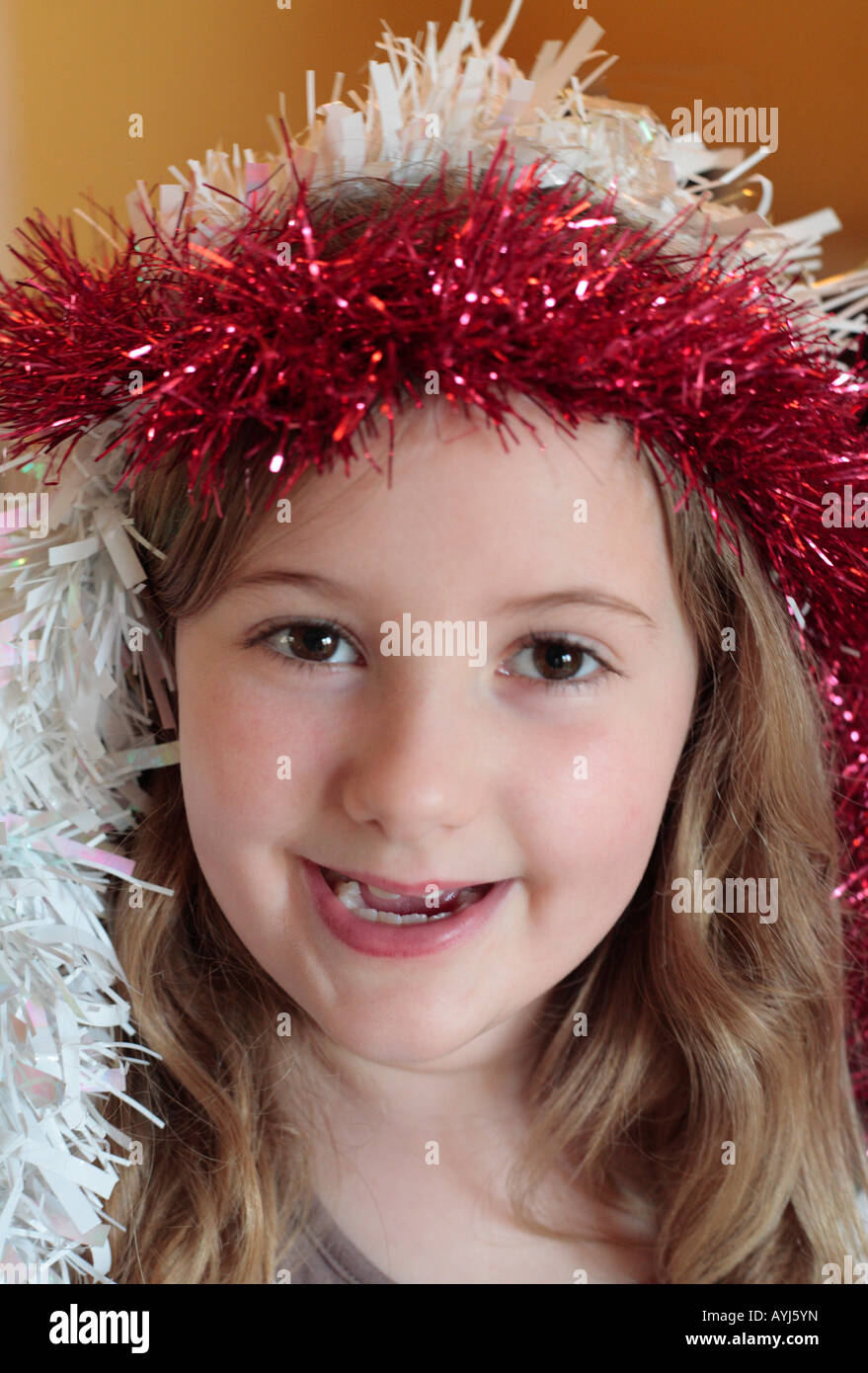 Headshot eines acht Jahre alten Mädchen lächelnd mit Lametta um ihren Kopf. Stockfoto