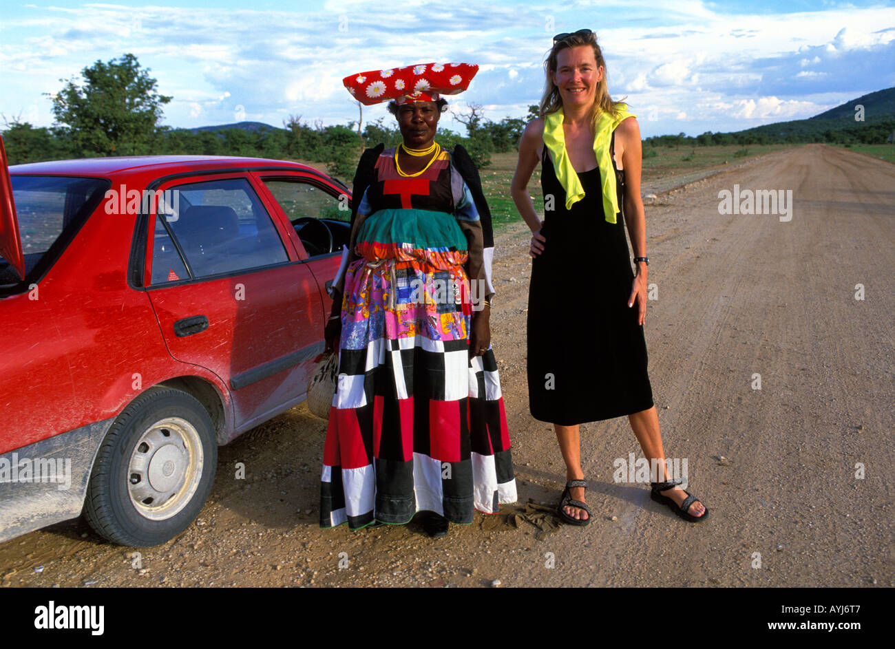 Kaokoveld eine Herero-Frau in traditioneller Kleidung, posiert für ein Foto mit einem Touristen Stockfoto