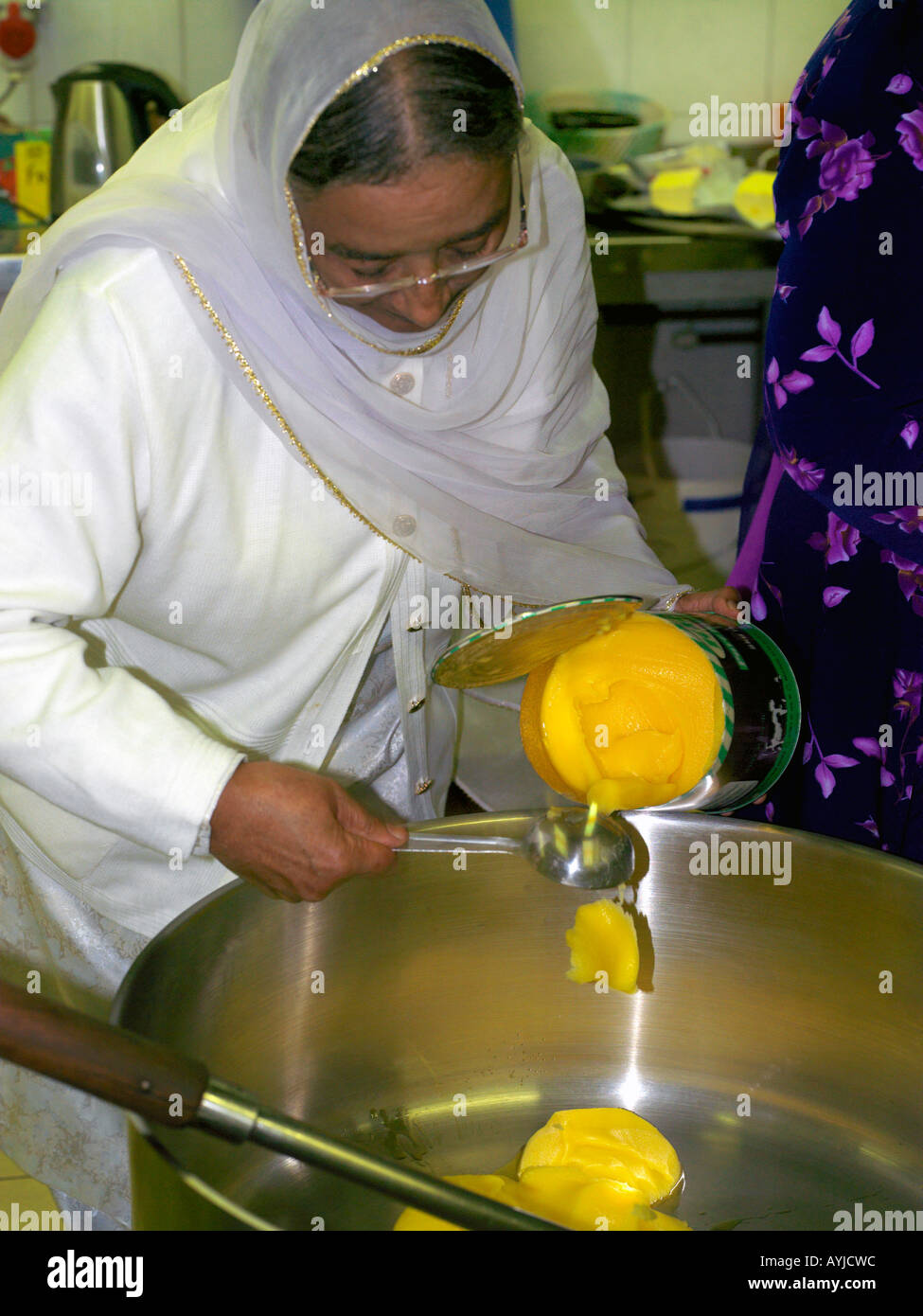 Khalsa Zentrum Tooting London England Frau in Küche Gießen Ghee in Pan am Jahrestag des Todes von Guru Tegh Bahadur Stockfoto