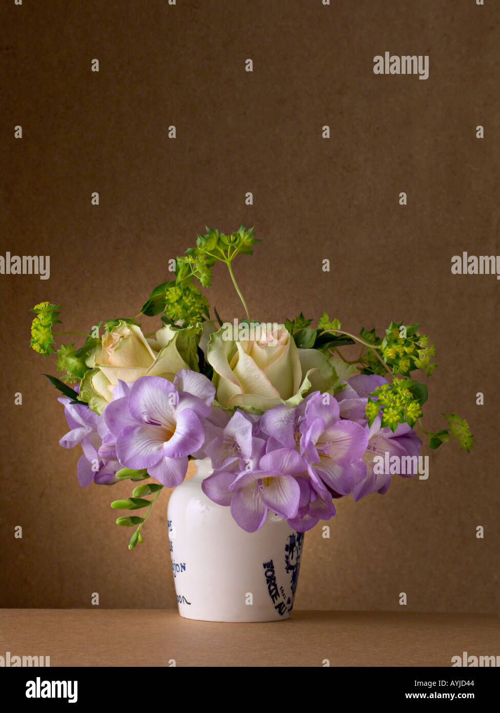 Ein Blumenstrauß aus Freesien Euphorbien und Rosen in einer alten Senf Topf Stockfoto