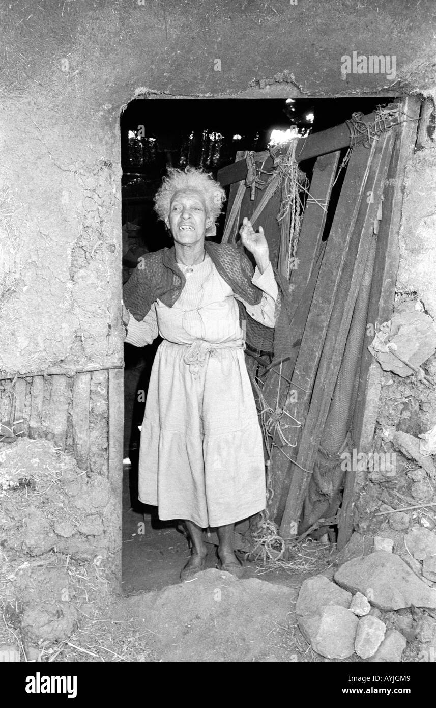 S/W einer älteren Frau, die in ihrer Tür gestikuliert und sich über die Lebensbedingungen in den Slums von Addis Abeba, Äthiopien, beschwert Stockfoto