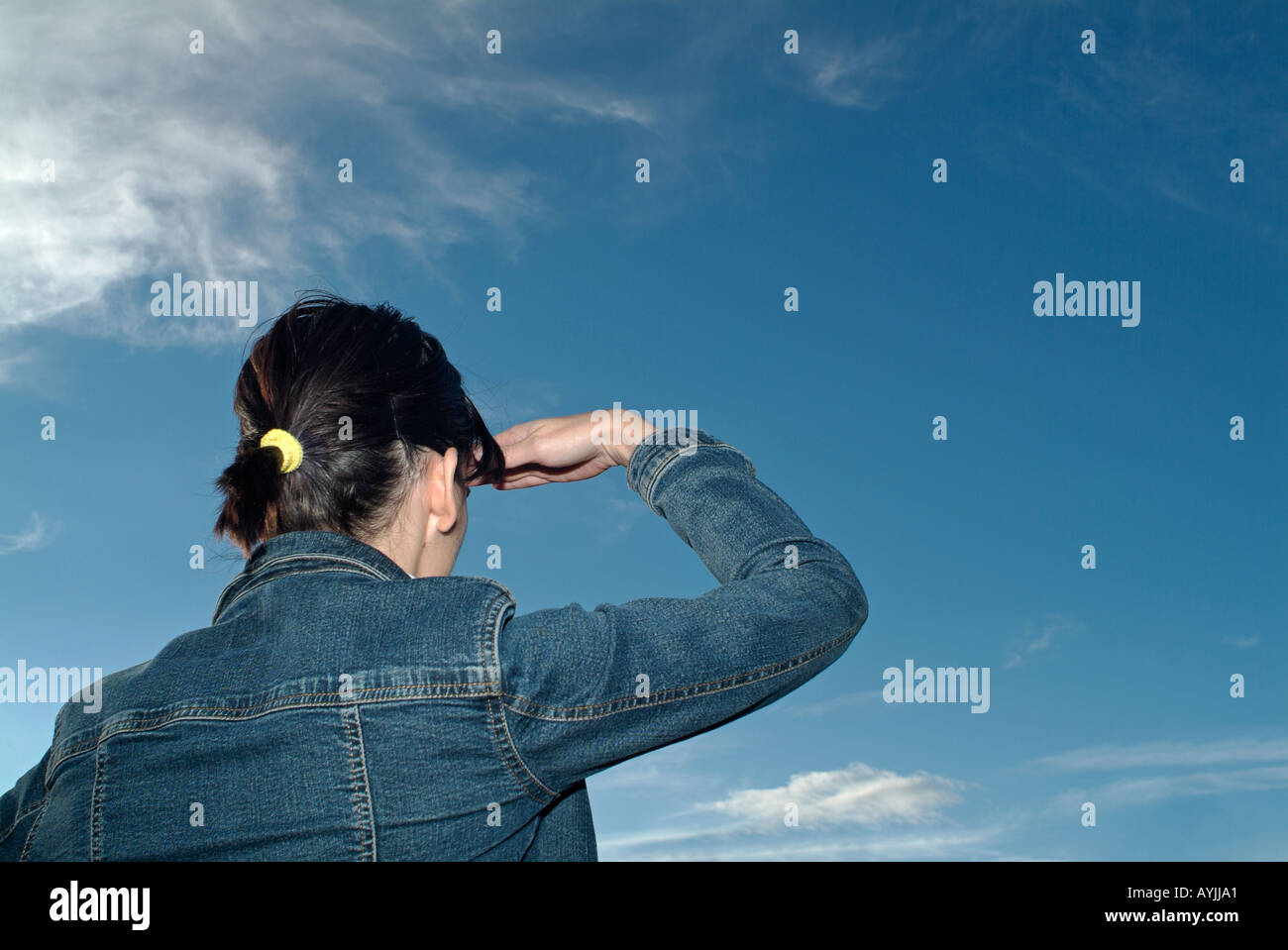 Woman Looking Out über einen blauen Wolkenhimmel, Rückansicht. Stockfoto